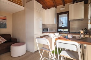 Une cuisine moderne avec des meubles blancs, un plan de travail en bois et un coin repas avec des chaises blanches.