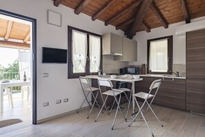 Eine moderne Küche mit Holzboden, einem Essbereich mit vier Stühlen und einem an der Wand montierten Fernseher.