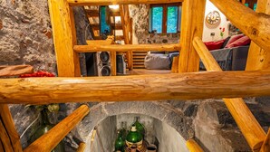 Un intérieur rustique avec des murs en pierre, des poutres en bois, un vieux puits en pierre et un coin salon accueillant.