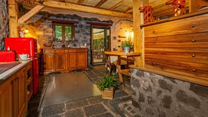 Une cuisine rustique avec des murs en pierre, des armoires en bois et un réfrigérateur rouge.