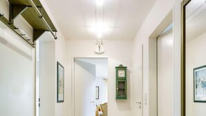 Un pasillo con un banco, un reloj y una puerta que da a otra habitación.