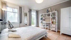 Un dormitorio con cama, escritorio, estantería y armario.