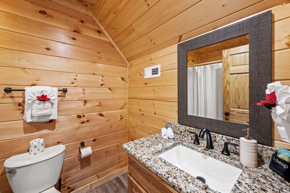 A wooden-paneled bathroom with a white sink, black faucet, and a large mirror. - Spring Deals with March, April, & May Dates • Smoky Mtn Cabin: Game Room/Hot Tub (Sevierville)