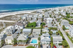 An aerial view of a coastal residential area with houses, a beach, and a train track.