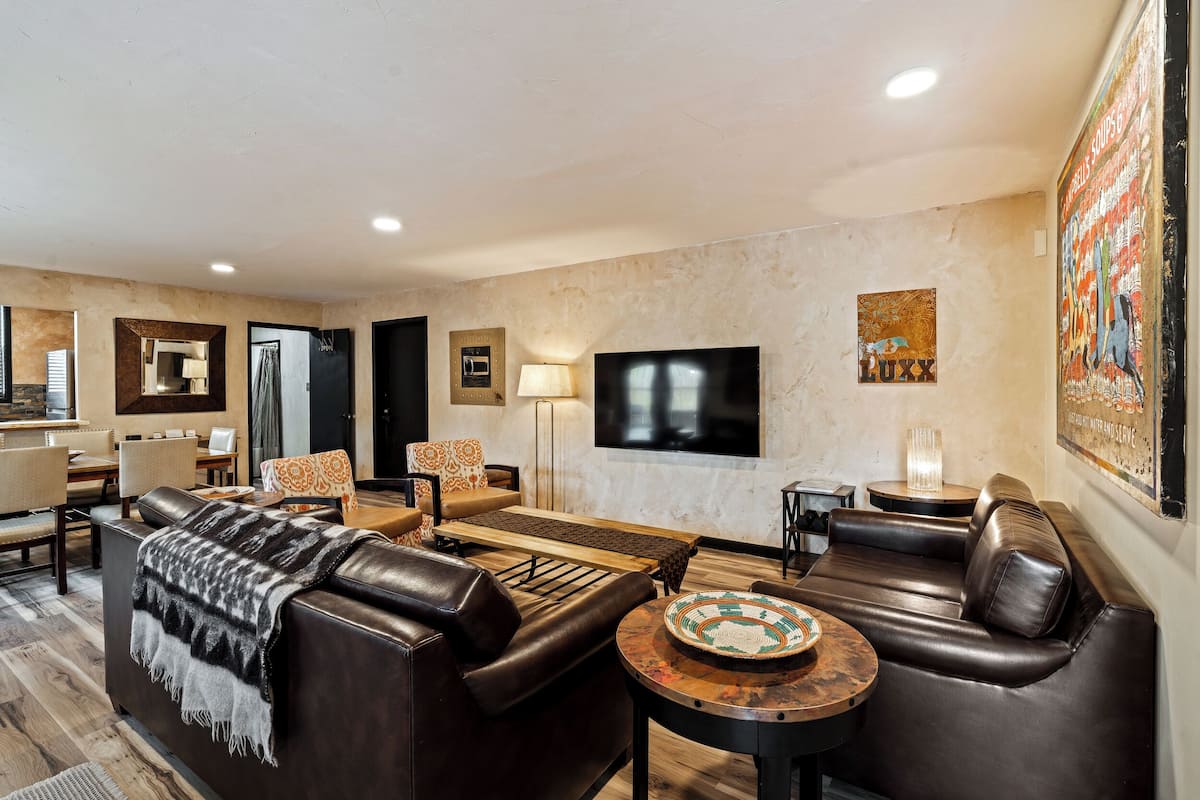 A modern living room with a fireplace, leather sofas, a coffee table, and a flat-screen TV.