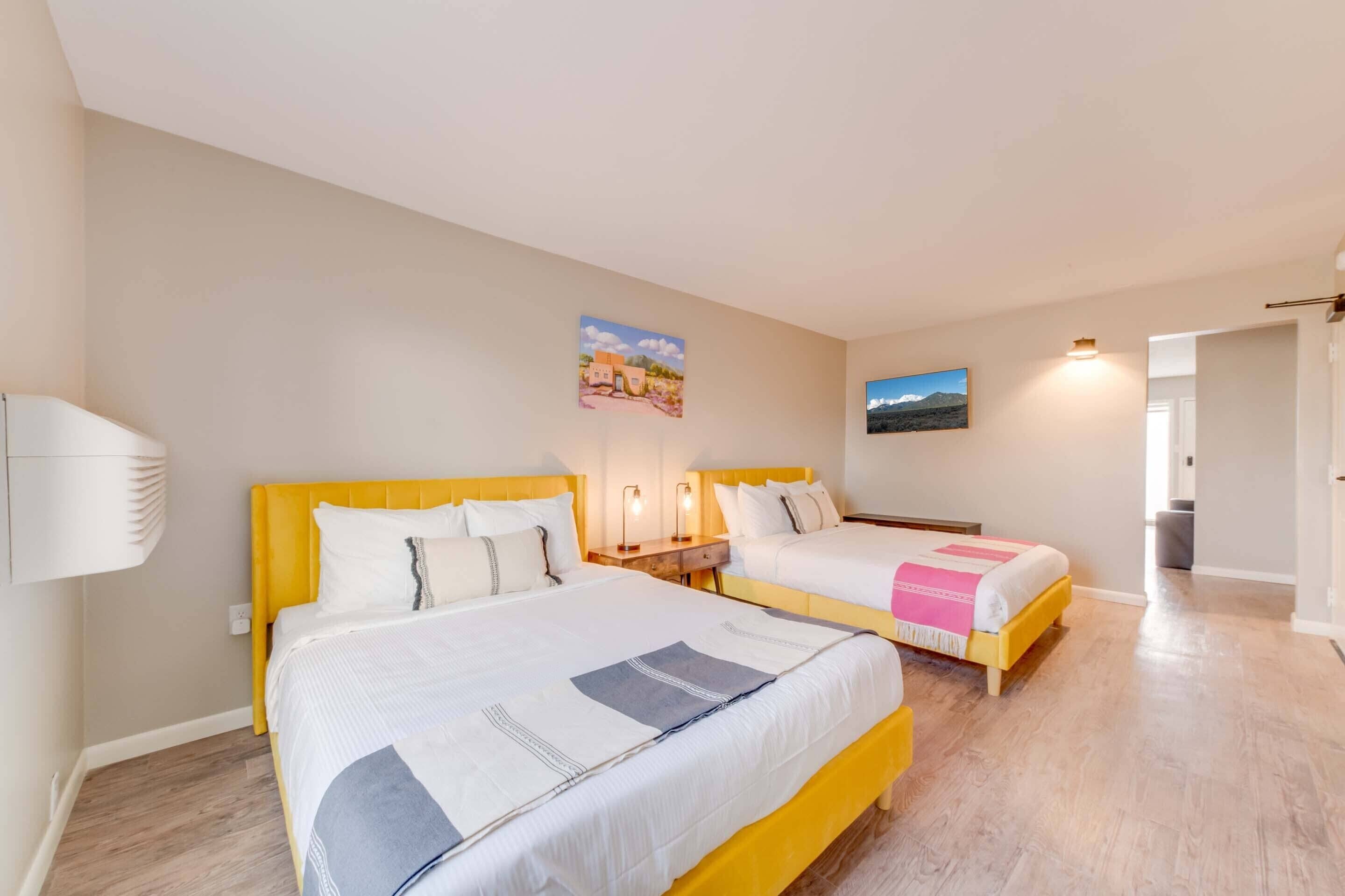 Une chambre d’hôtel avec deux lits, chacun doté d’une tête de lit, de tables de chevet et de lampes.