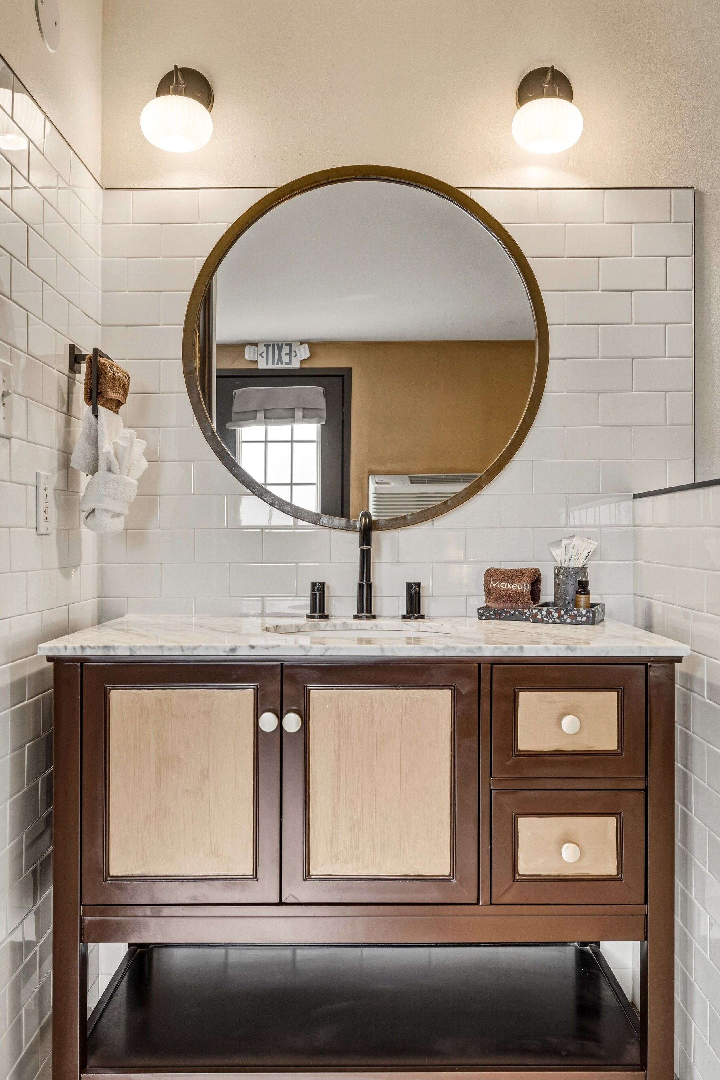 A bathroom with a round mirror, a sink, and a vanity with drawers.