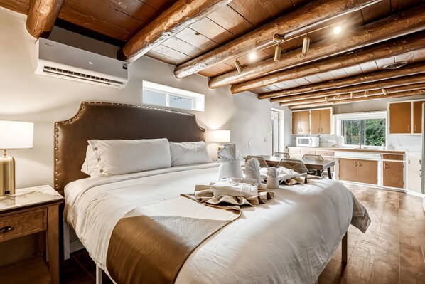 Een hotelkamer met een groot bed, een houten plafond, een raam en een kitchenette.