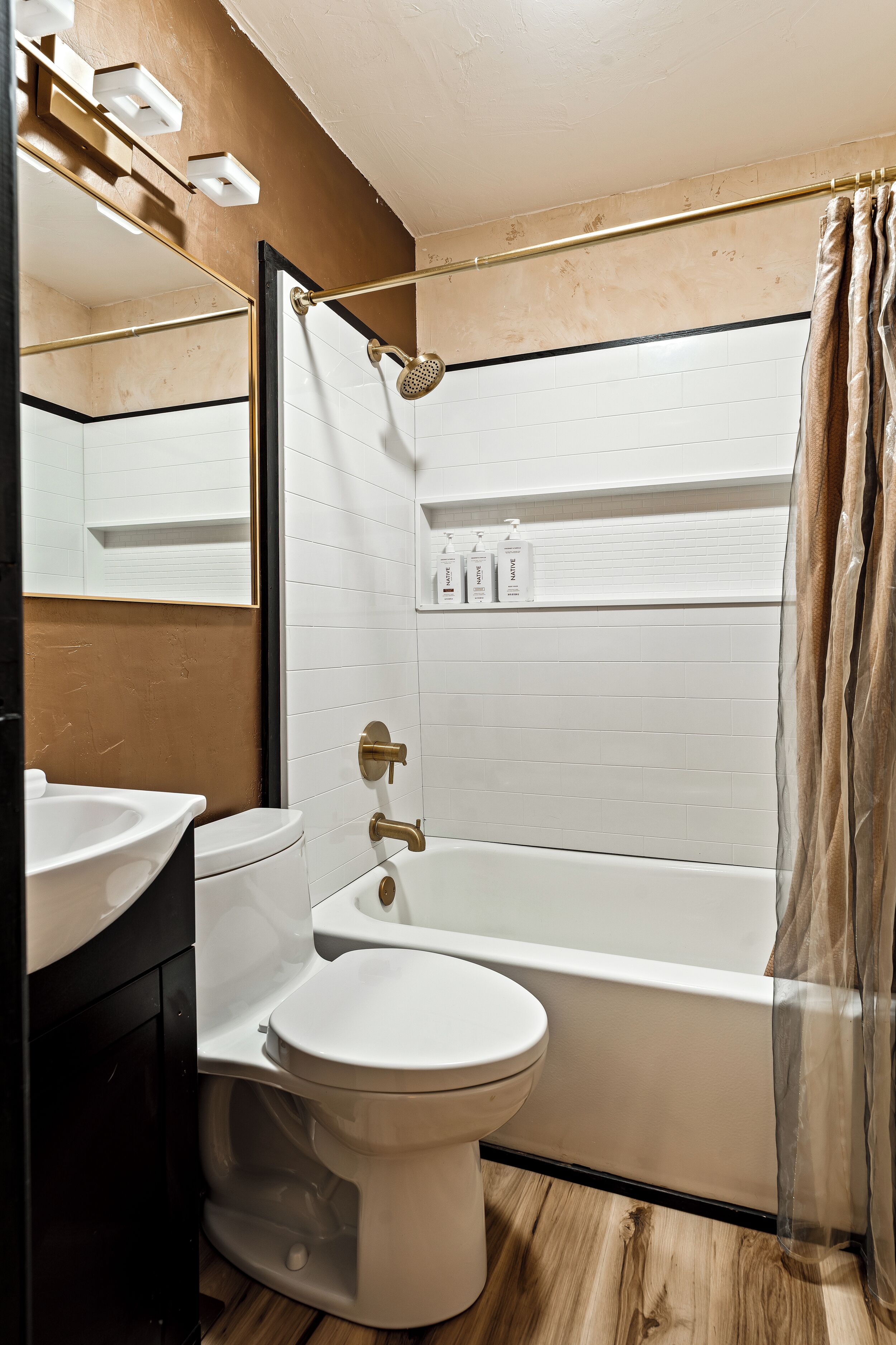 Un baño moderno con inodoro blanco, bañera y zona de ducha.