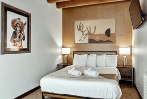 Une chambre d’hôtel avec un lit, deux lampes de chevet, une œuvre d’art encadrée au mur et une table de chevet.