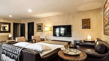 Habitación de hotel con cama, sofá, televisor, lámpara y un cuadro en la pared.
