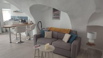 Een moderne woonruimte met een bank, salontafel en een eethoek met stoelen en een tafel.