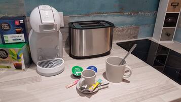 A kitchenette with a coffee maker, toaster, and two cups on the counter.