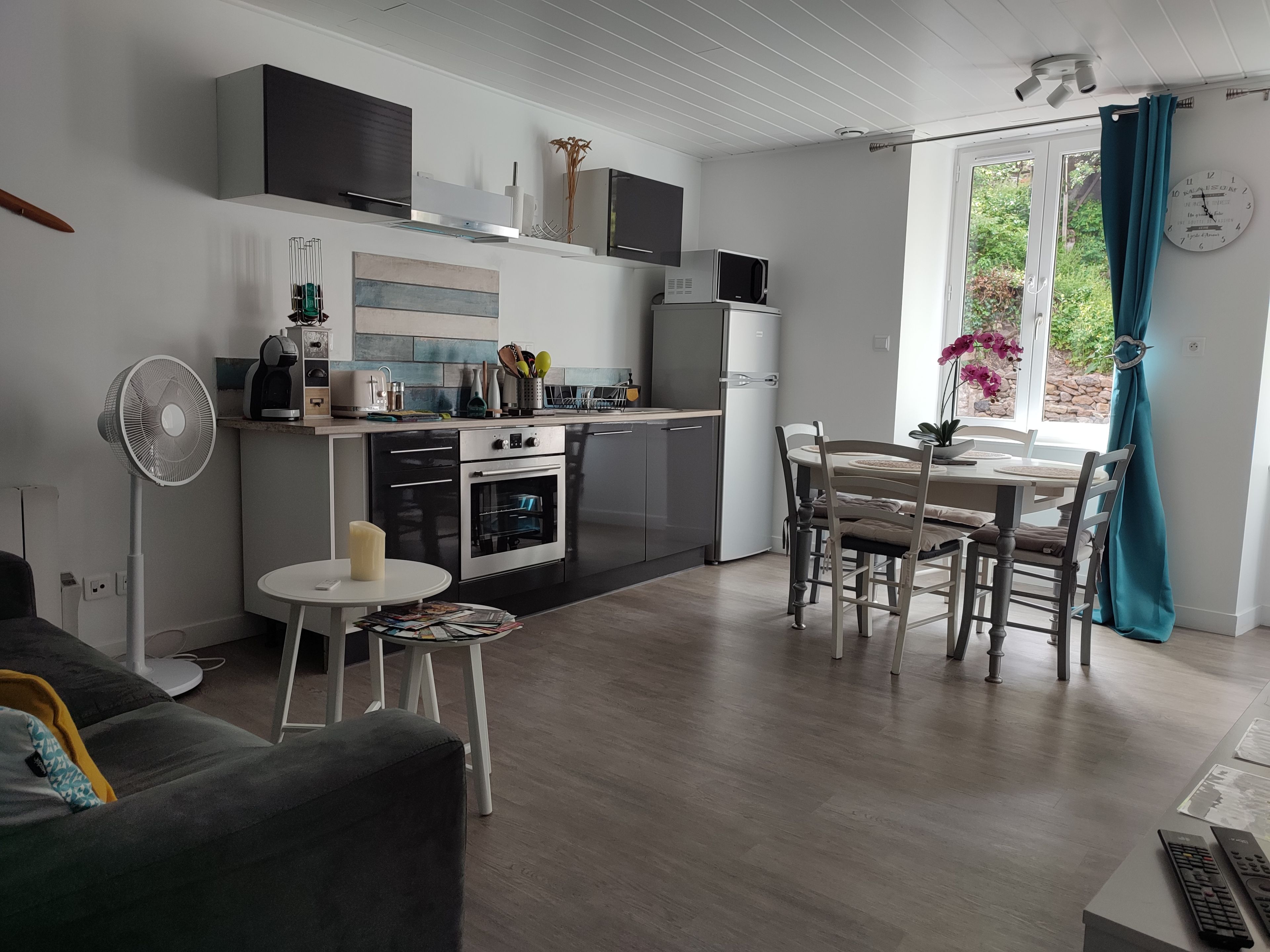 Een moderne keuken met een eethoek, een ventilator en een klok aan de muur.