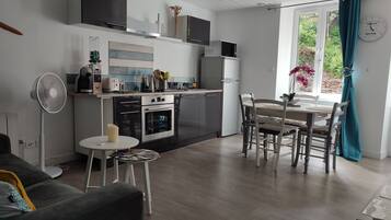 Een moderne keuken met een eethoek, een ventilator en een klok aan de muur.