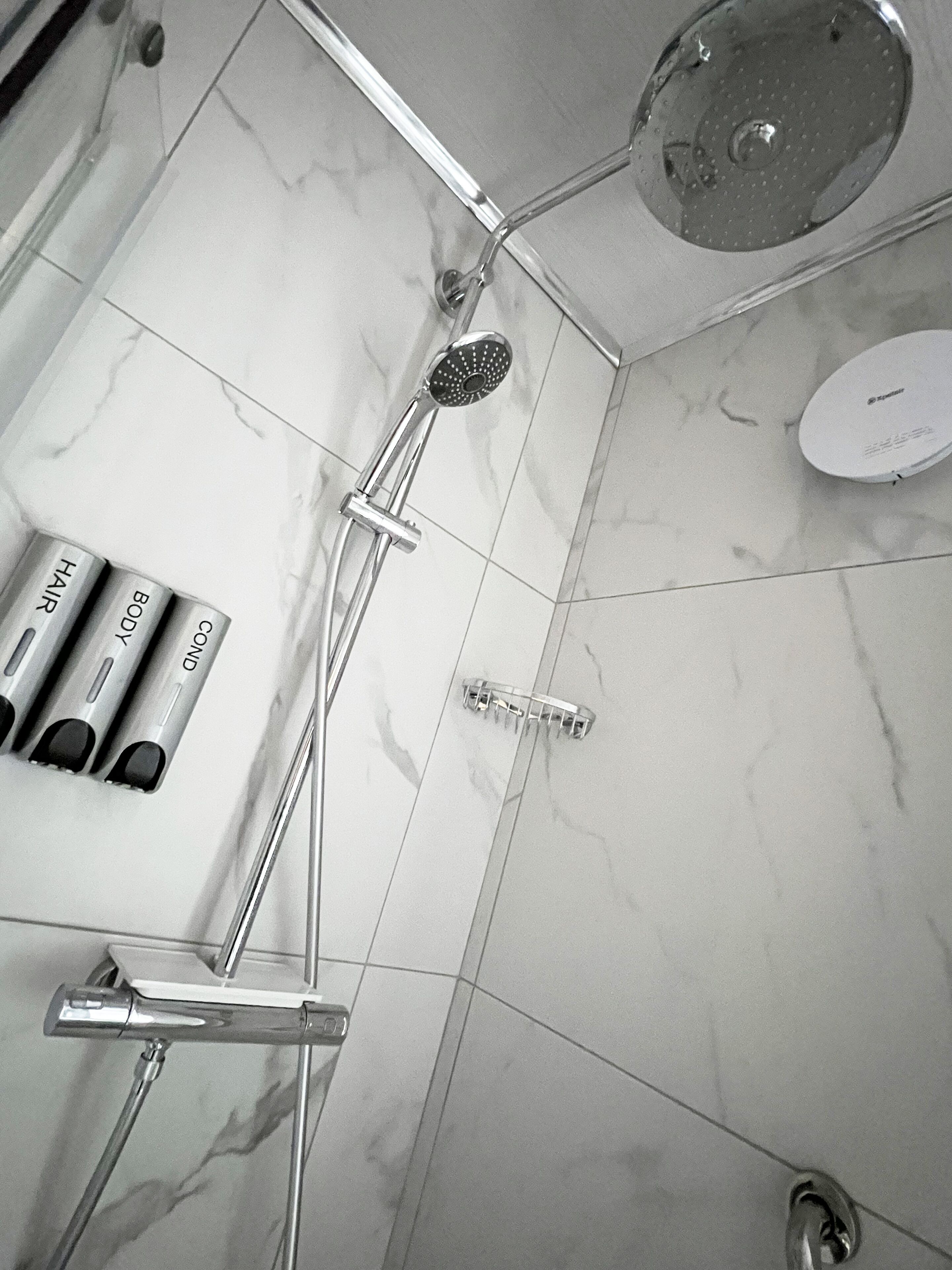 Une salle de bain avec une douche, des toilettes et un lavabo. On trouve des articles de toilette sur le lavabo.
