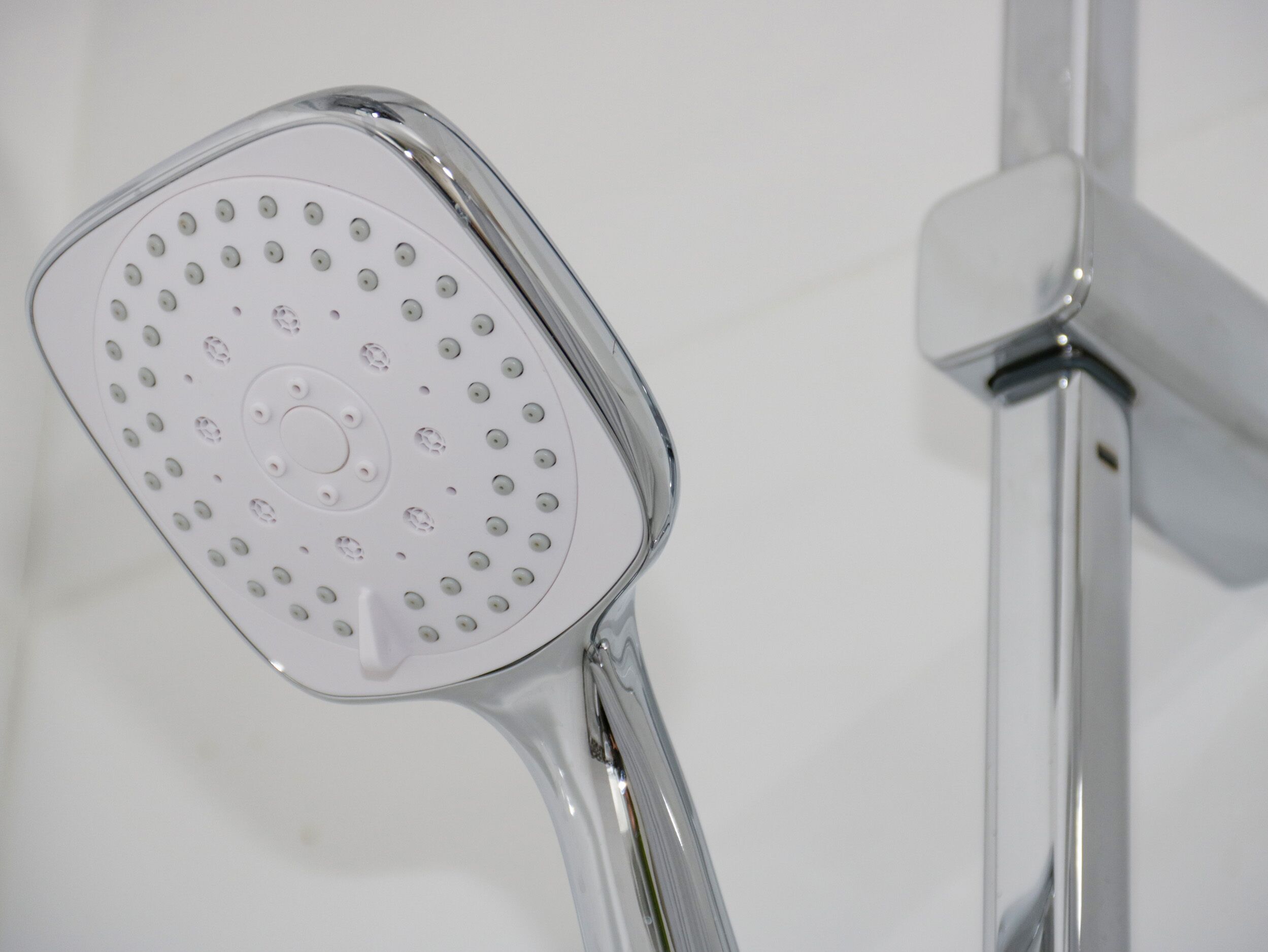 Un cabezal de ducha con un diseño circular de orificios, sujeto a un accesorio de cromo.