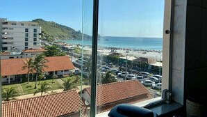 A view from a window overlooking a beach with buildings and parked cars. - VISTA INCRIVEL PRAIA GRANDE (Arraial do Cabo)