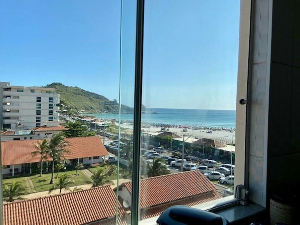 A view from a window overlooking a beach with buildings and parked cars.