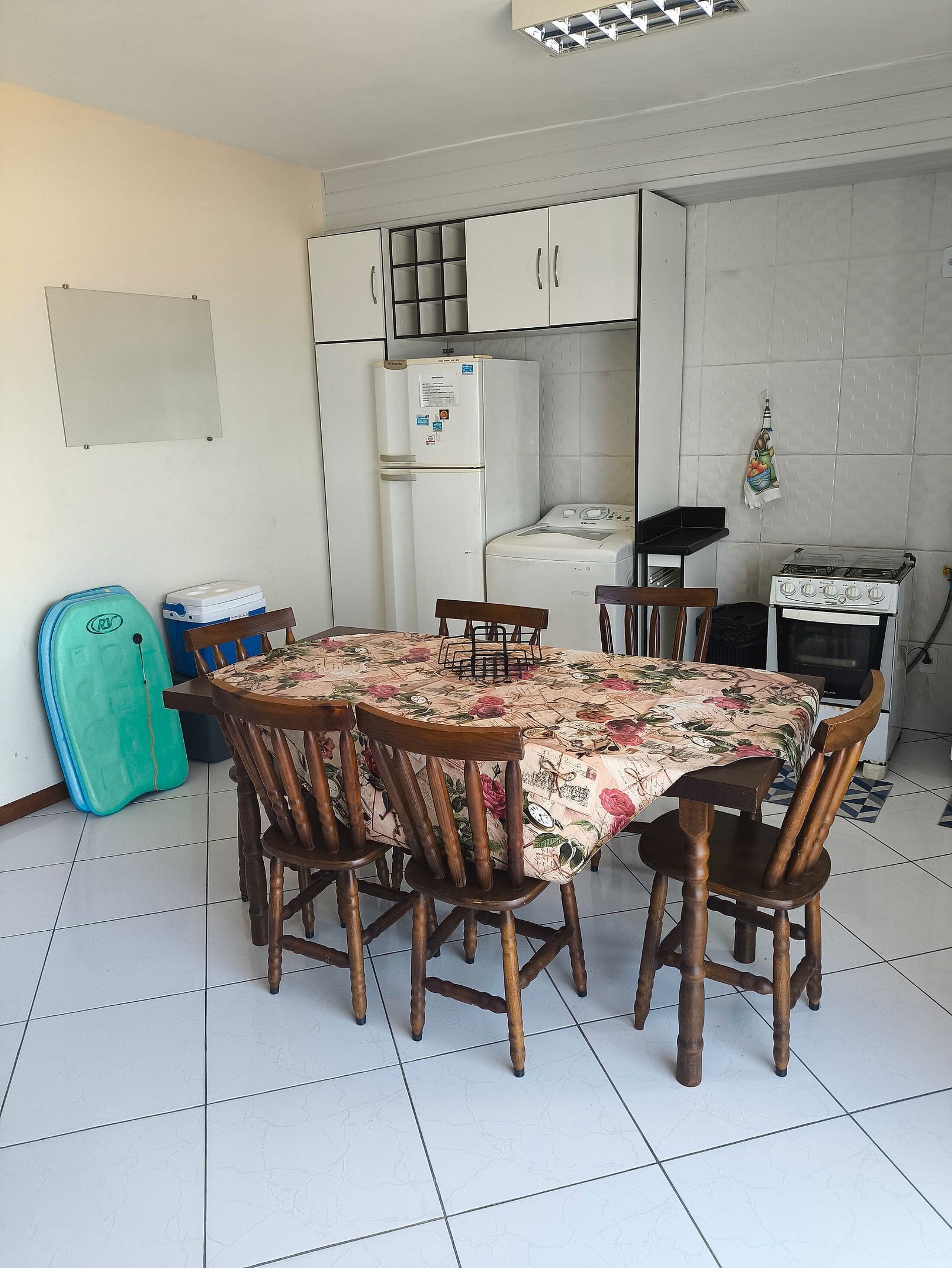 A compact kitchen with a dining table, chairs, a refrigerator, a washing machine, and a gas stove.