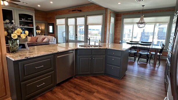 A modern kitchen with dark cabinetry, a granite countertop, and a large island. - 200 feet on the water with boat house!!! (Hackberry)