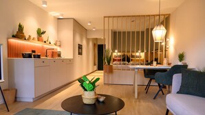 Un salon moderne avec un canapé, une table basse agrémentée d’une plante, et un coin repas comprenant une table et des chaises.