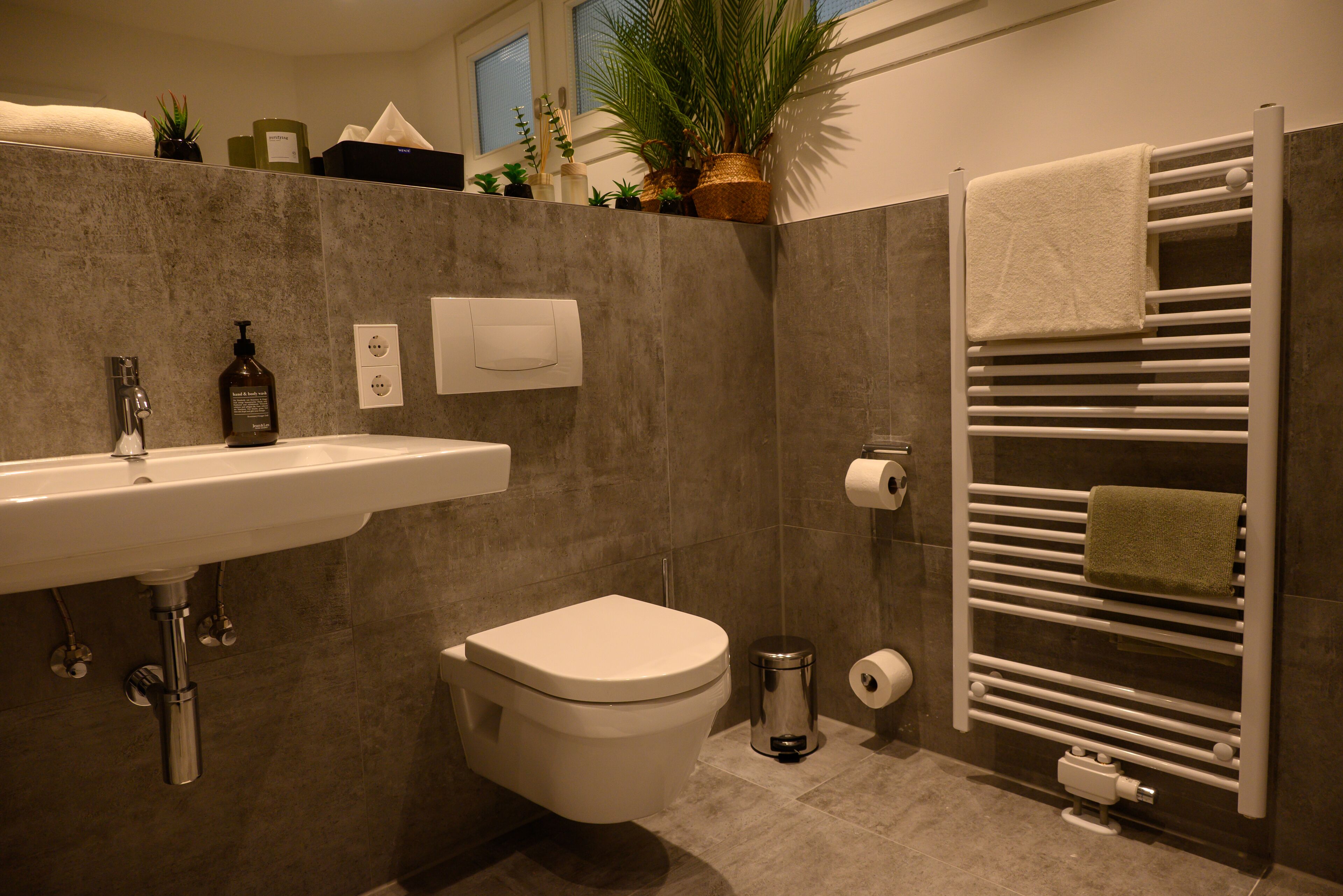 A modern bathroom with a white sink, toilet, and towel rack.