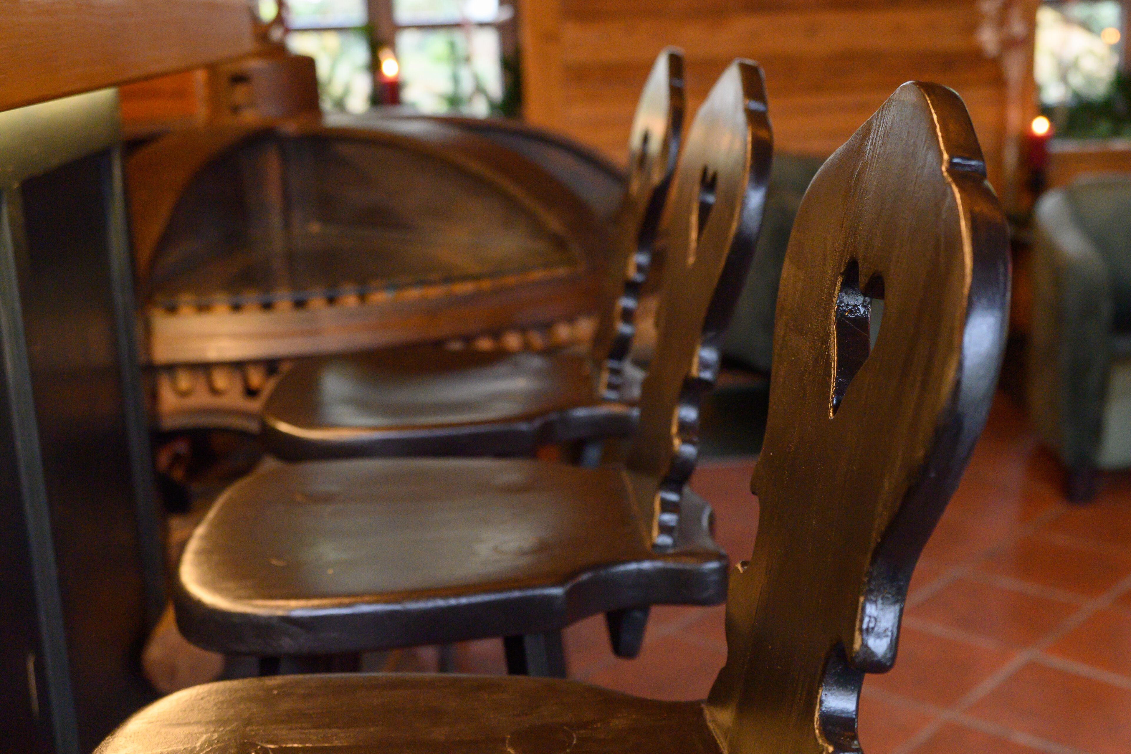 Sillas de madera con estructura metálica y un banco en un interior rústico.