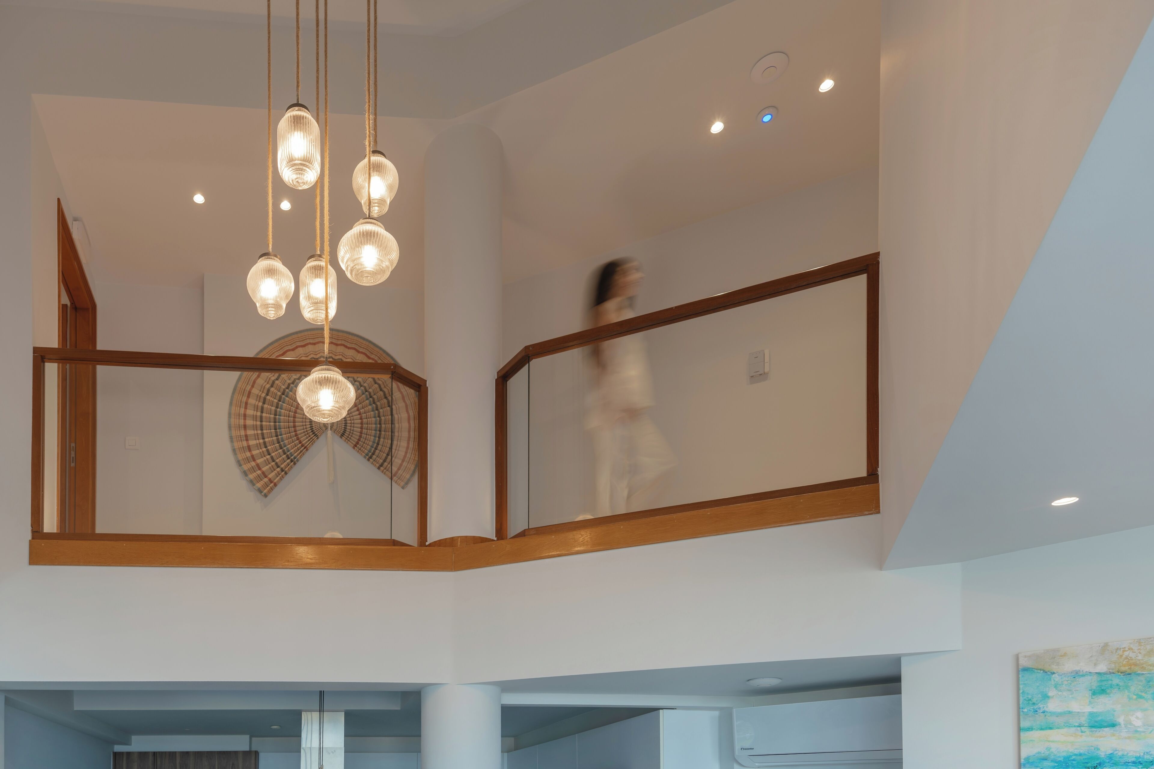 A modern interior with a central light fixture, a staircase, and a view of the lower level.