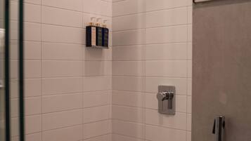 A small, tiled shower room with a glass door, a showerhead, and a towel rack.