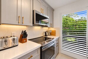 A modern kitchen with white cabinetry, a built-in oven, a stovetop, and a toaster.