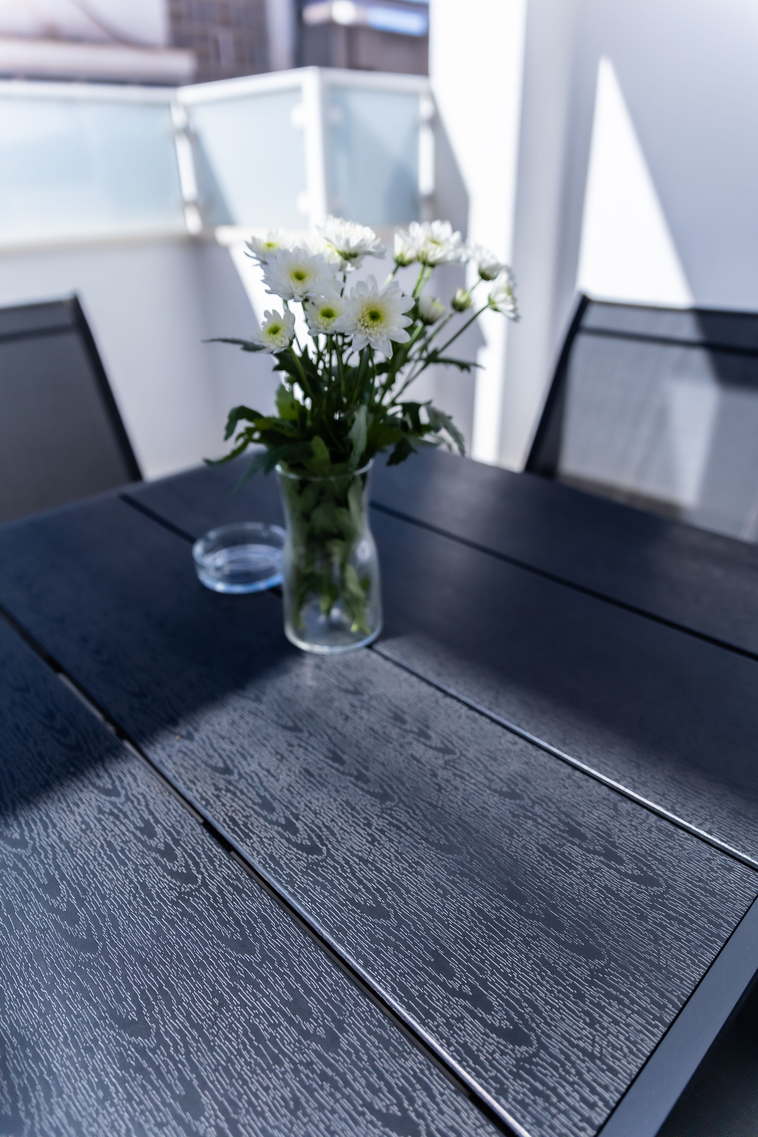 A table with a glass vase containing white flowers.