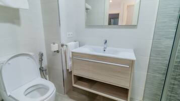 Un baño moderno con inodoro, lavamanos y ducha.