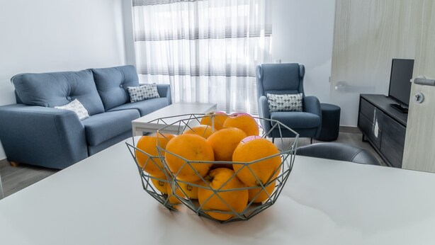 Een moderne woonkamer met een bank, fauteuil en een tafel met een fruitmand.