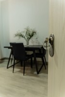 Una puerta con un ojo de cerradura y un llavero que dice "Bap-B" en una habitación con una mesa de comedor y sillas.