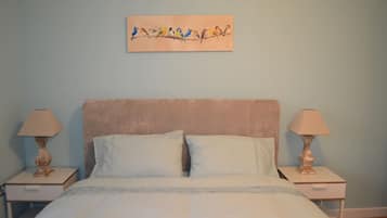 Een slaapkamer met een bed, twee nachtkastjes, twee lampen en een schilderij aan de muur.