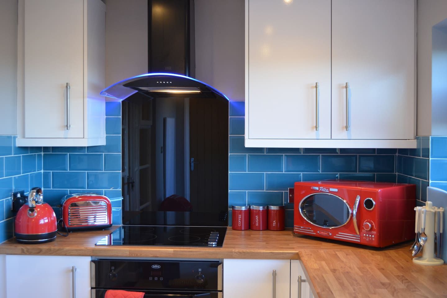 Une cuisine moderne avec une hotte noire, un grille-pain rouge et un four à micro-ondes rouge.