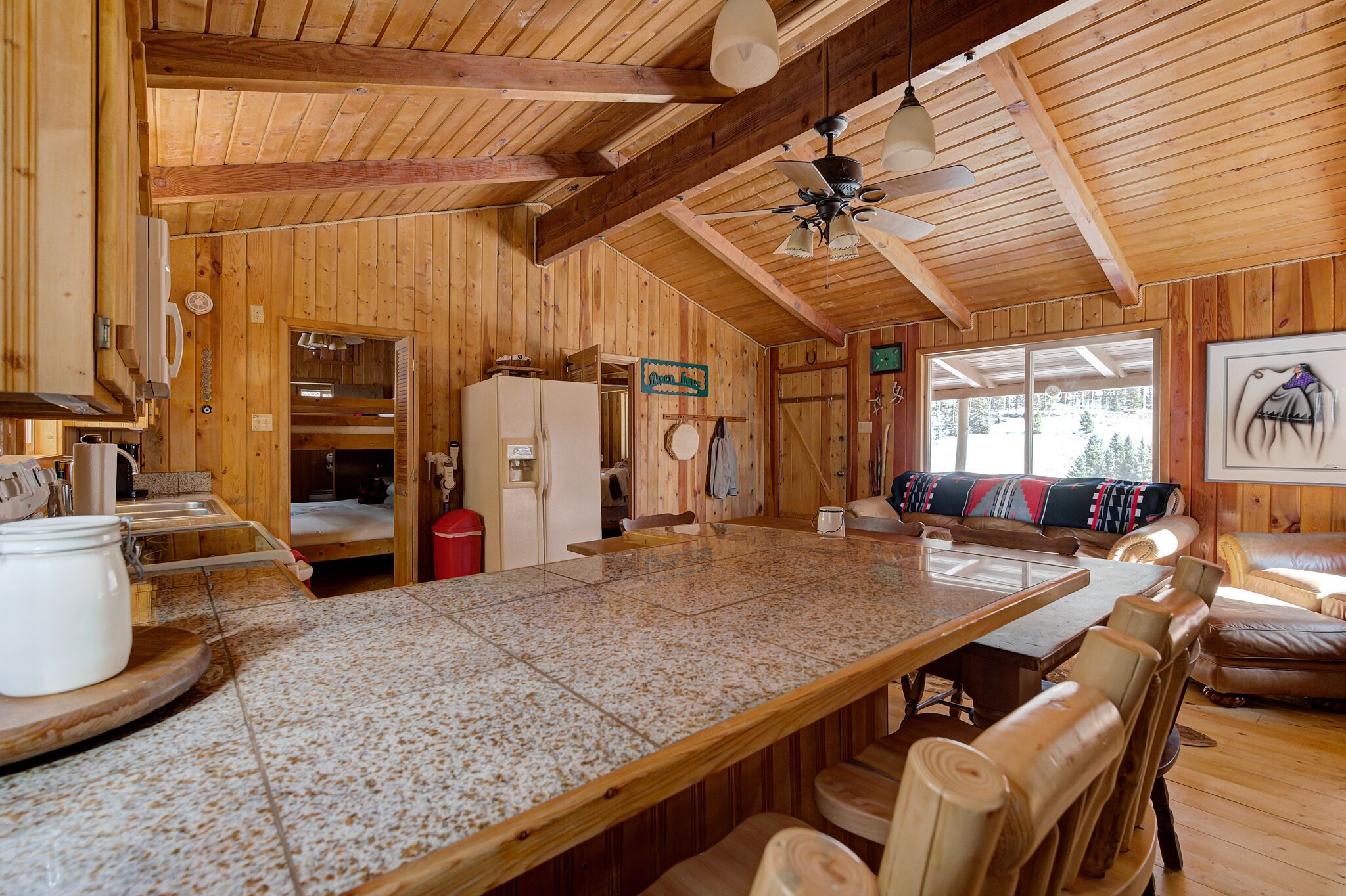 A wooden cabin interior with a large kitchen island, dining area, and seating space.