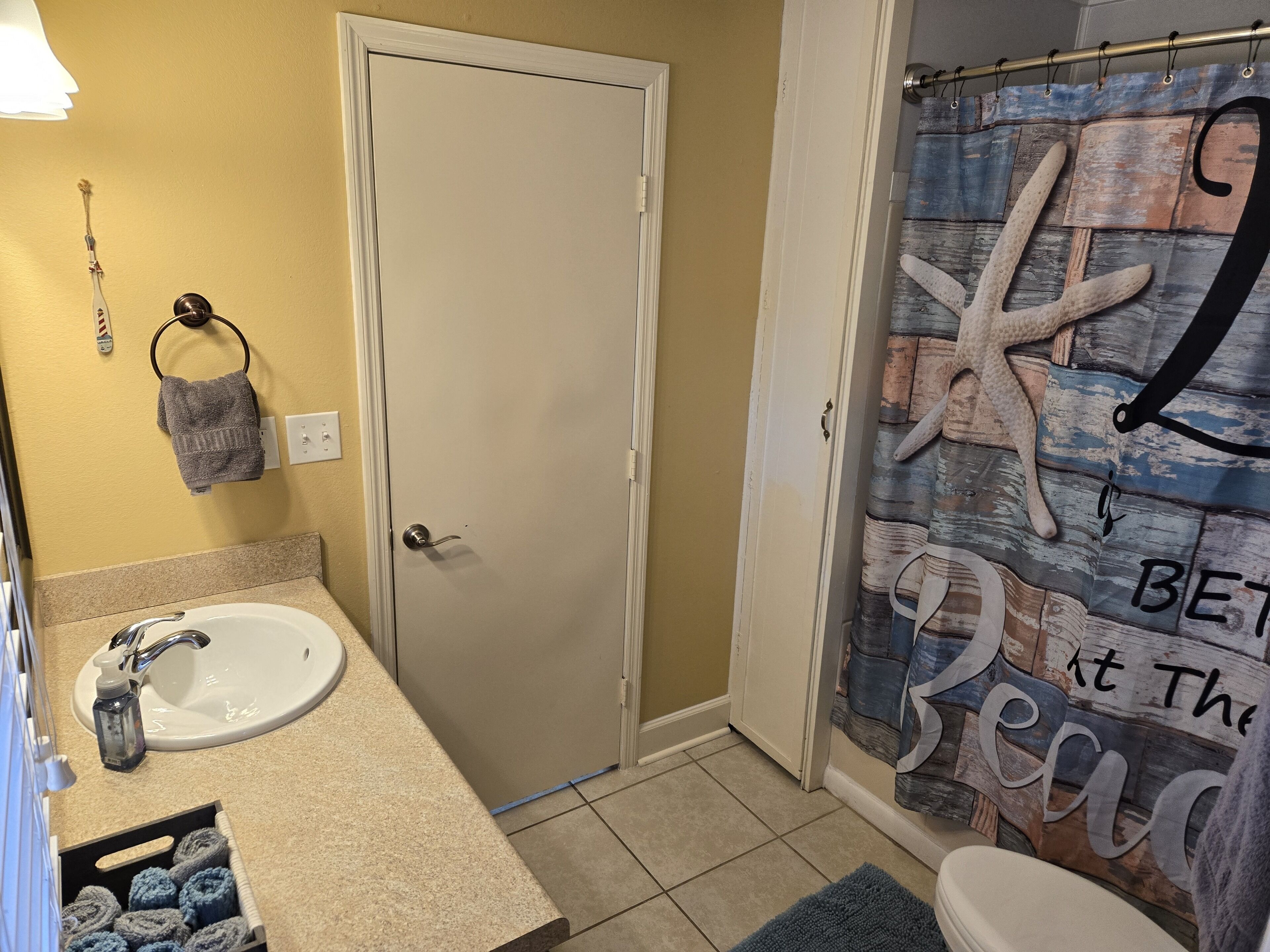 Une salle de bain équipée d’un lavabo, de toilettes et d’un rideau de douche, le tout décoré sur le thème de la mer.