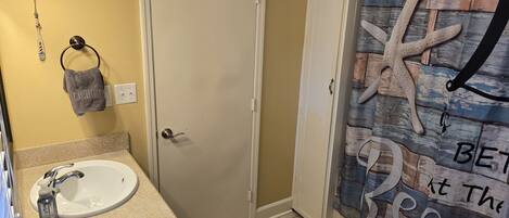 Une salle de bain équipée d’un lavabo, de toilettes et d’un rideau de douche, le tout décoré sur le thème de la mer.