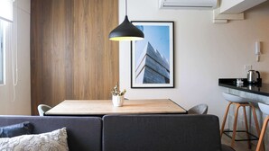 A modern kitchen with a wooden accent wall, a dining area with a table and chairs, and a bar stool.