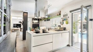 Eine moderne Küche mit Kochinsel, Einbauherd und großem Fenster mit Blick auf einen Balkon.