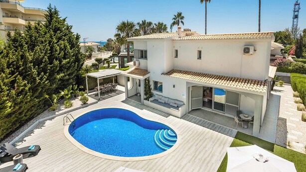 Eine moderne Villa mit Swimmingpool, Sitzgelegenheiten im Freien und Meerblick.