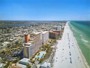 A coastal hotel with multiple floors, a swimming pool, and a beach view.