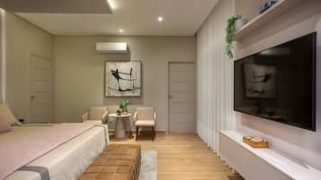 Een moderne slaapkamer met een bed, een televisie, een klein tafeltje en een stoel.