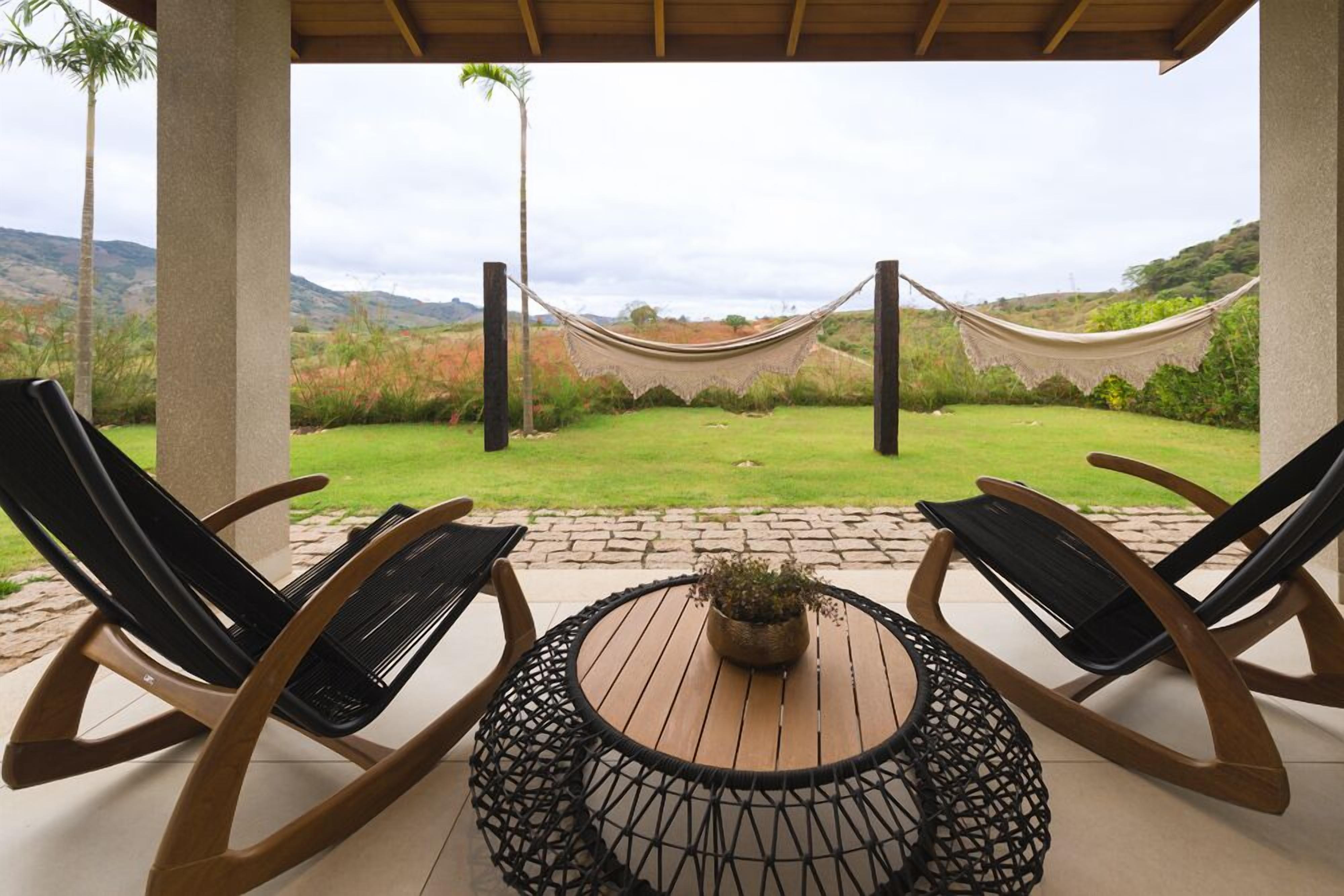 A patio with two rocking chairs, a round table with a plant, and a hammock.