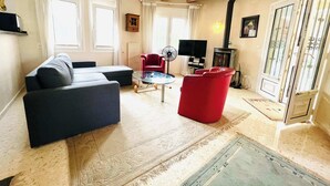 A living room with a sofa, red chair, TV, fireplace, and large windows. - T-0622, Evelyn, villa with private pool in Dènia (Denia)