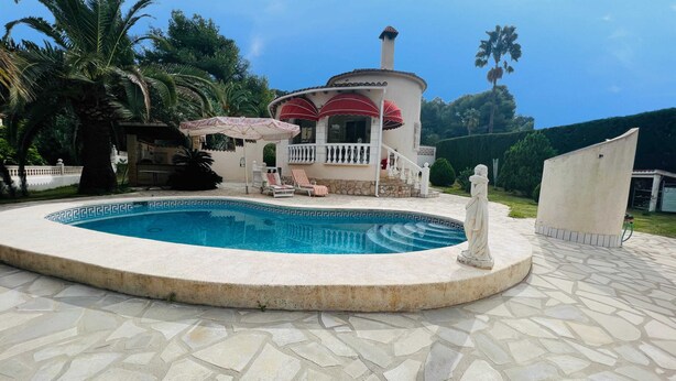 A swimming pool with a stone deck, a statue, and a building with a red roof in the background. - T-0622, Evelyn, villa with private pool in Dènia (Denia)