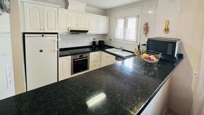 A kitchen with white cabinets, a black countertop, a stove, and a microwave. - T-0622, Evelyn, villa with private pool in Dènia (Denia)