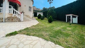 A residential property with a stone staircase leading to a white door, a red awning, and a well-maintained lawn with a small shed. - T-0622, Evelyn, villa with private pool in Dènia (Denia)